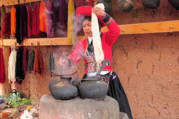 Woman cooking with traditional clothing who use words in Quechua to talk with tourists