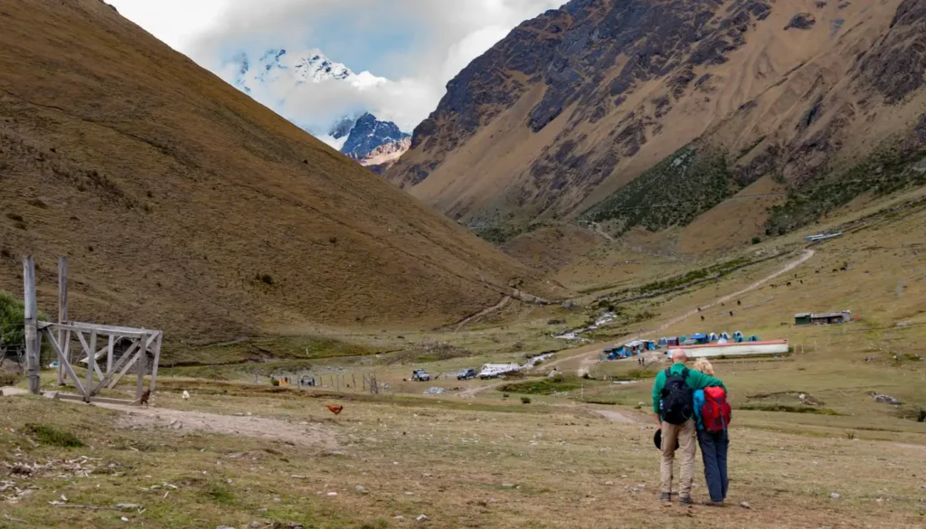 hiking couple admiring a snowy mountain, salkantay, peru